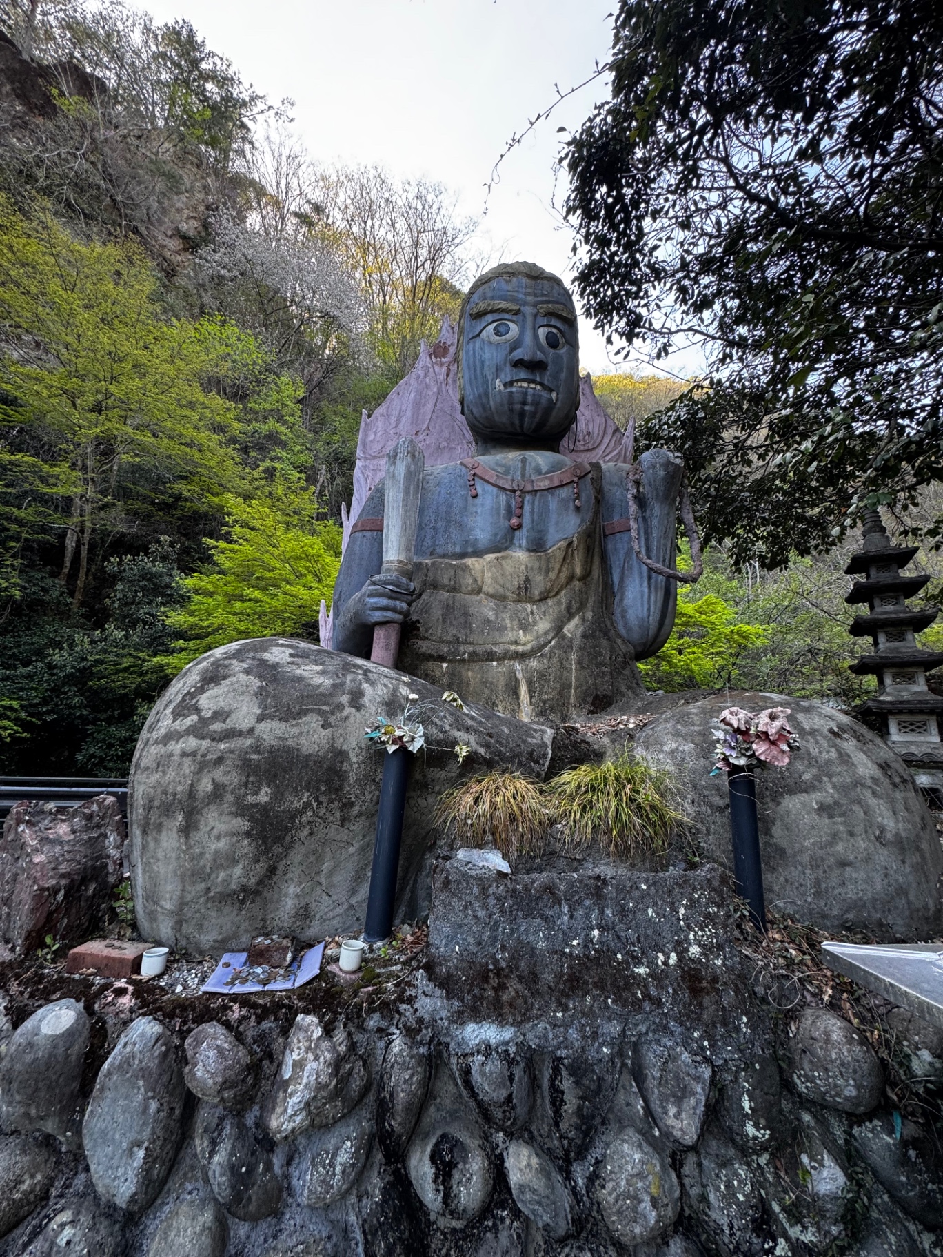 Große Fudō-Myōō-Statue mit Schwert vor einem bewaldeten Berghang in Japan