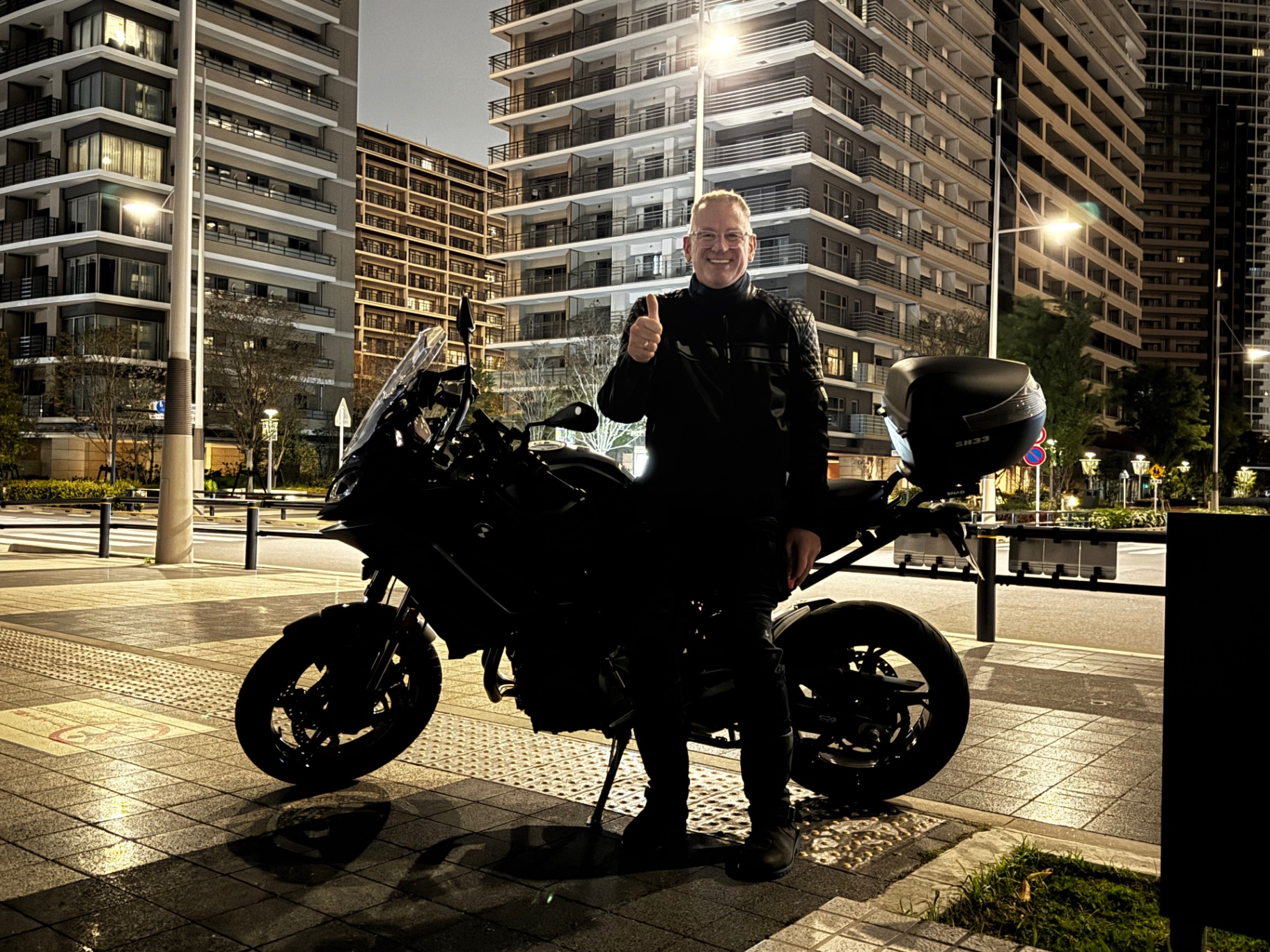 Mit dem Motorrad vor beleuchteten Hochhäusern in Tokio bei Nacht
